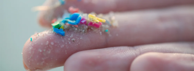 A person's fingers holding microplastics waste.