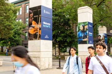 student walk past the front gate of the University of Toronto