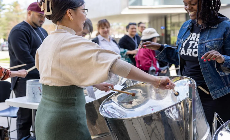 Two people trying out steel drumming.