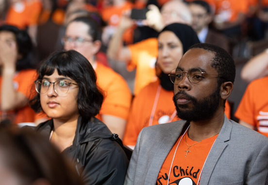 People sitting at an event wearing orange shirts