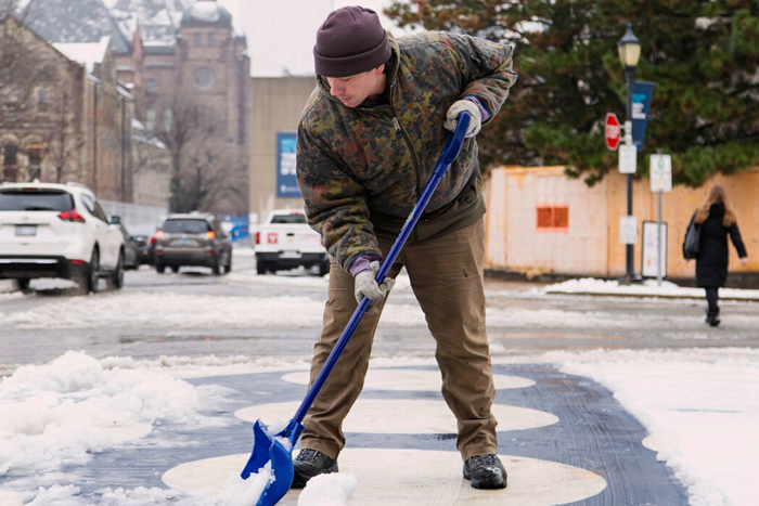 A person shovels snow on campus