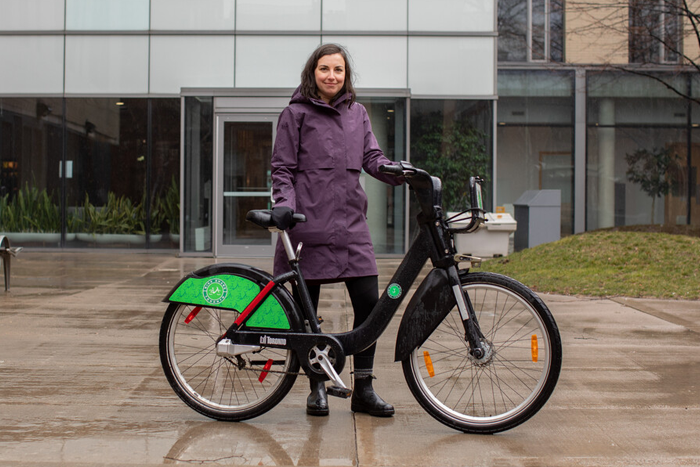 A person holds the handlebars and while standing behind a bicycle