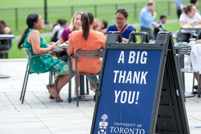 A sign reads "a big thank you" and people sit at a table behind it