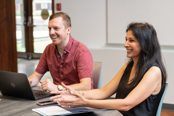 Two people sit at a table in a meeting