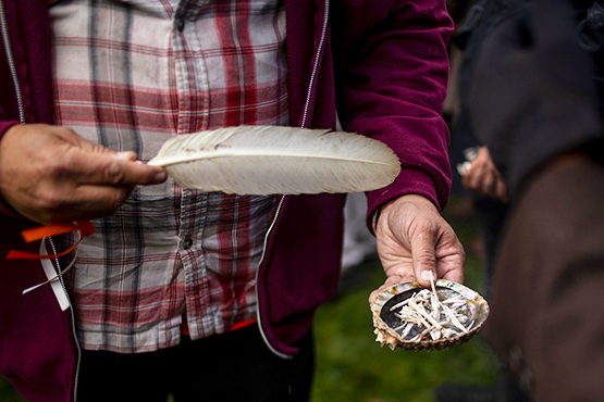 A smuding ceremony where a man holds a feather