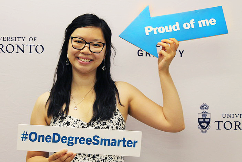 a recent grad holding two signs