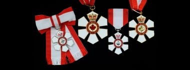 Four Order of Canada medals on a black background.