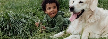 a young boy with a dog lying down in a field