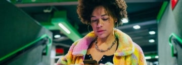 young mixed race woman uses a cellphone while walking through a subway station