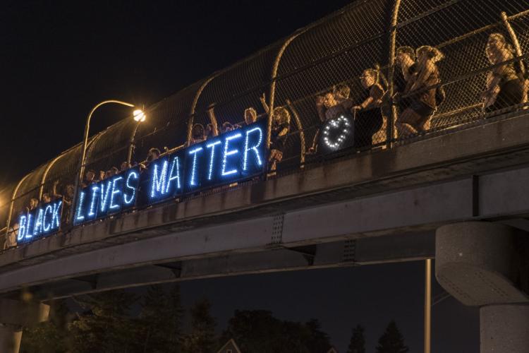 BLM supporters with a lit up Black Lives Matter sign on a bridge in Milwaukee