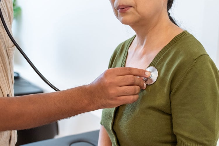 a doctor examines the heart of a south asian woman with a stethoscope