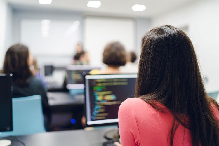 a woman sits in a computer science classroom