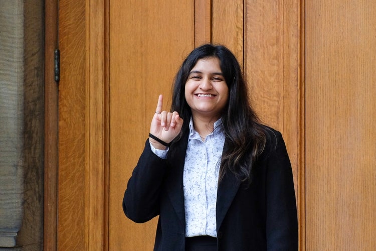 Vishakha Pujari holds up her pinky finger with her engineering ring outside of convocation hall at the University of Toronto