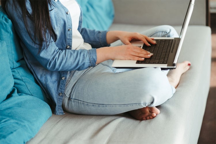 young woman sitting on sofa using a laptop