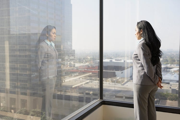 a female executive looks out a corner office window