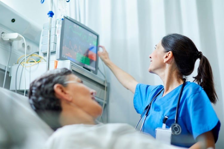 A female doctor checks a computer screen next to a patient in a hospital