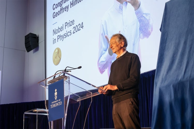 Hinton speaking at the podium during the event