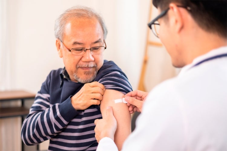 older man recieves a flu shot from a doctor