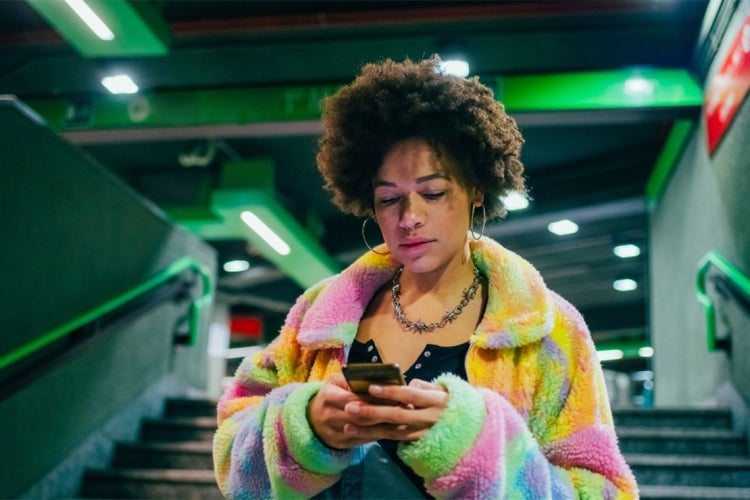 young mixed race woman uses a cellphone while walking through a subway station