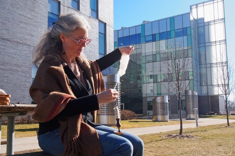 Nicole Klenk weaves on a bench outside at UTSC campus