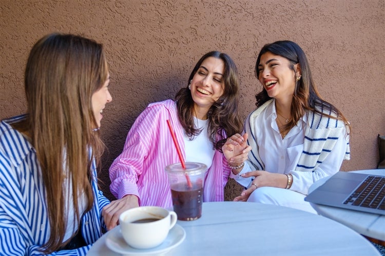 a group of young women laughing over a cup of coffee