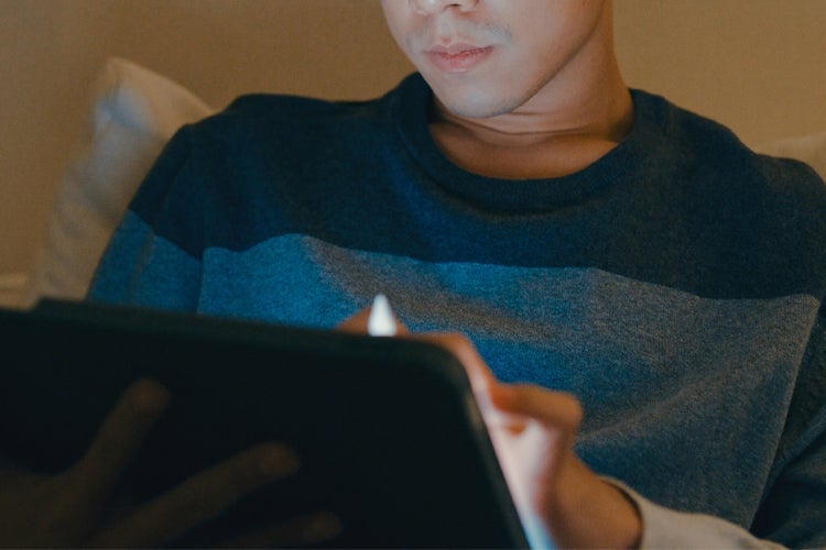 young man typing on a tablet while at home