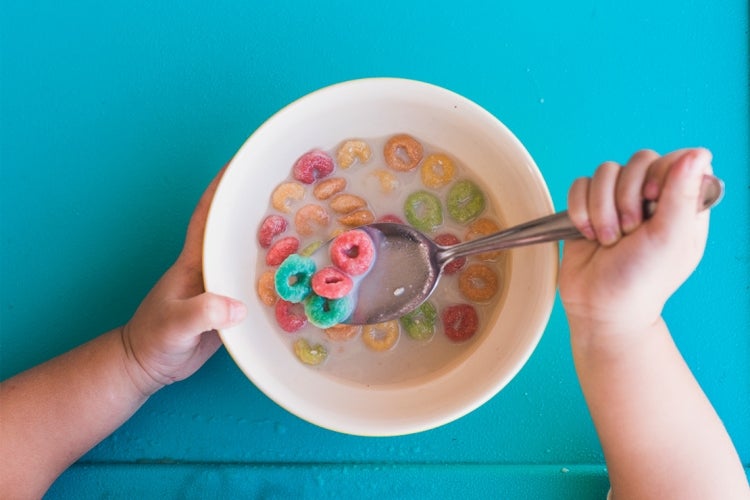 a toddler eats sugary cereal with a spoon