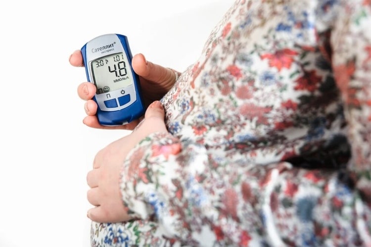 a pregnan woman holds a blood sugar monitor