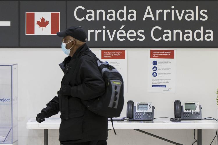 A passenger walks in front of an airport arrivals sign