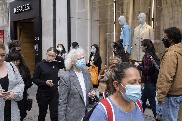 crowd of people of mixed ages and race, masked and unmasked shopping on a high street