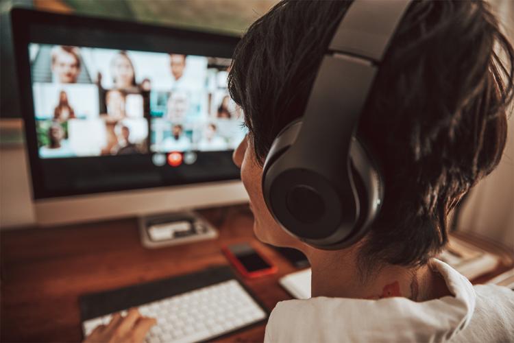 A person wears headphones while participating in a group video conference call