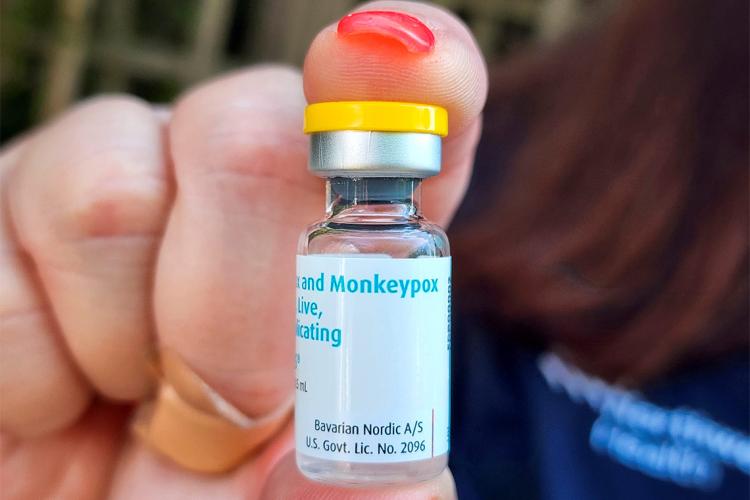 a person holds up a vial of monkeypox vaccine