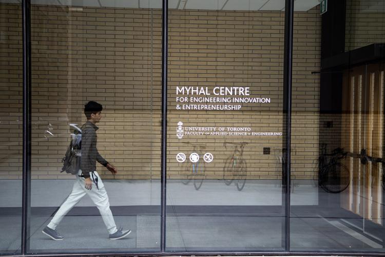 A student walks behind a glass wall at U of T's Myhal Centre