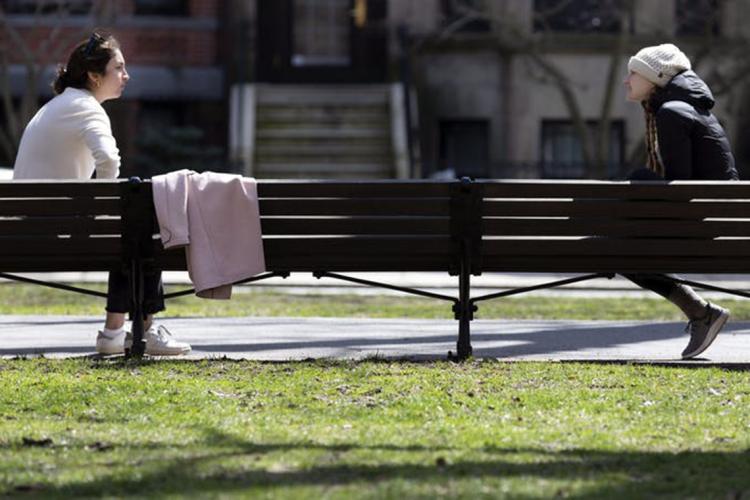 Two people on park benches separated by a distance of about 7 feet