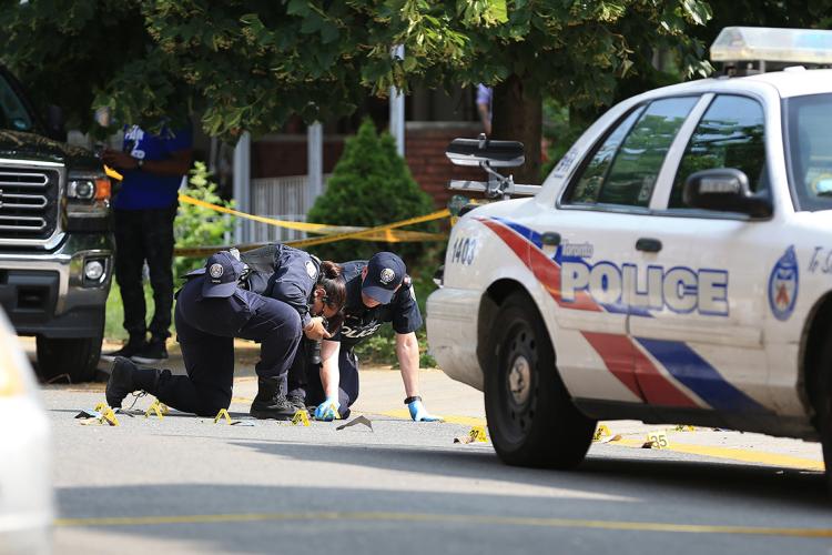 Photo of Toronto police examining shells and blood stains on street after shooting