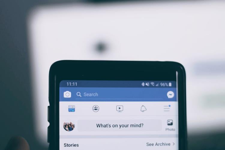 close up of smartphone with facebook app up. Text on screen reads "what's on your mind?"