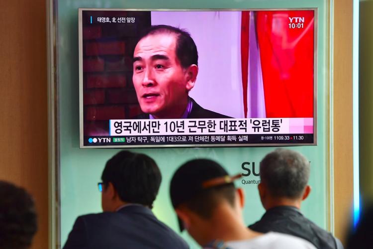 People watch a television news broadcast showing file footage of Thae Yong-Ho, North Korea's deputy ambassador to Britain