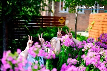 Two students hiding in the flowers, making peace signs