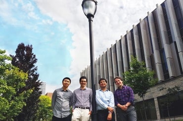 Photo of four engineering students standing by lamp post