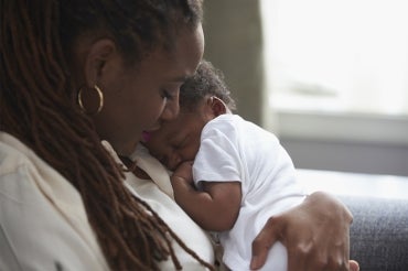 A woman holds her newborn baby close to her