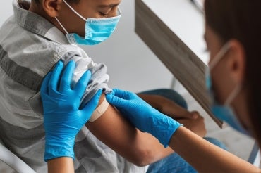 child gets a band aid on their arm after receiving a vaccination