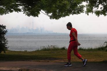 an elderly woman jogs along the waterfront on Toronto Island