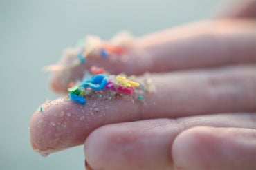 hand holding up microplastics on fingertips