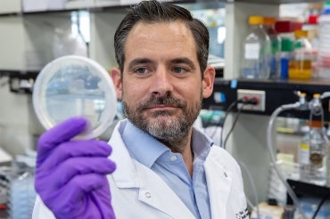 Daniel Schramek examines a petri dish