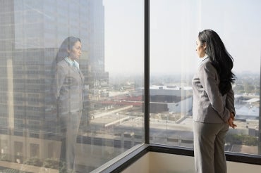 a female executive looks out a corner office window