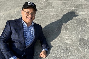 Eugene Choi lies down beside his named tile outside of convocation hall