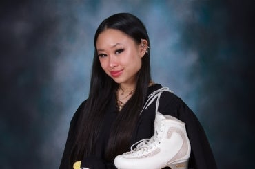Xin Yi Lim wears a graduation robe and a pair of figure skates