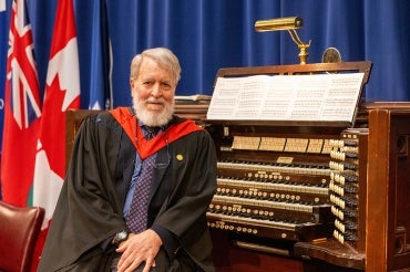 John Tuttle sits in front of the organ at Convocation Hall