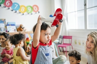 young boy plays with a toy airplane in a daycare setting