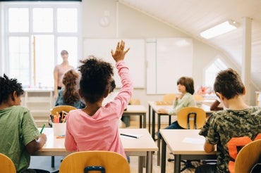 young female student raises her hand in a classroom